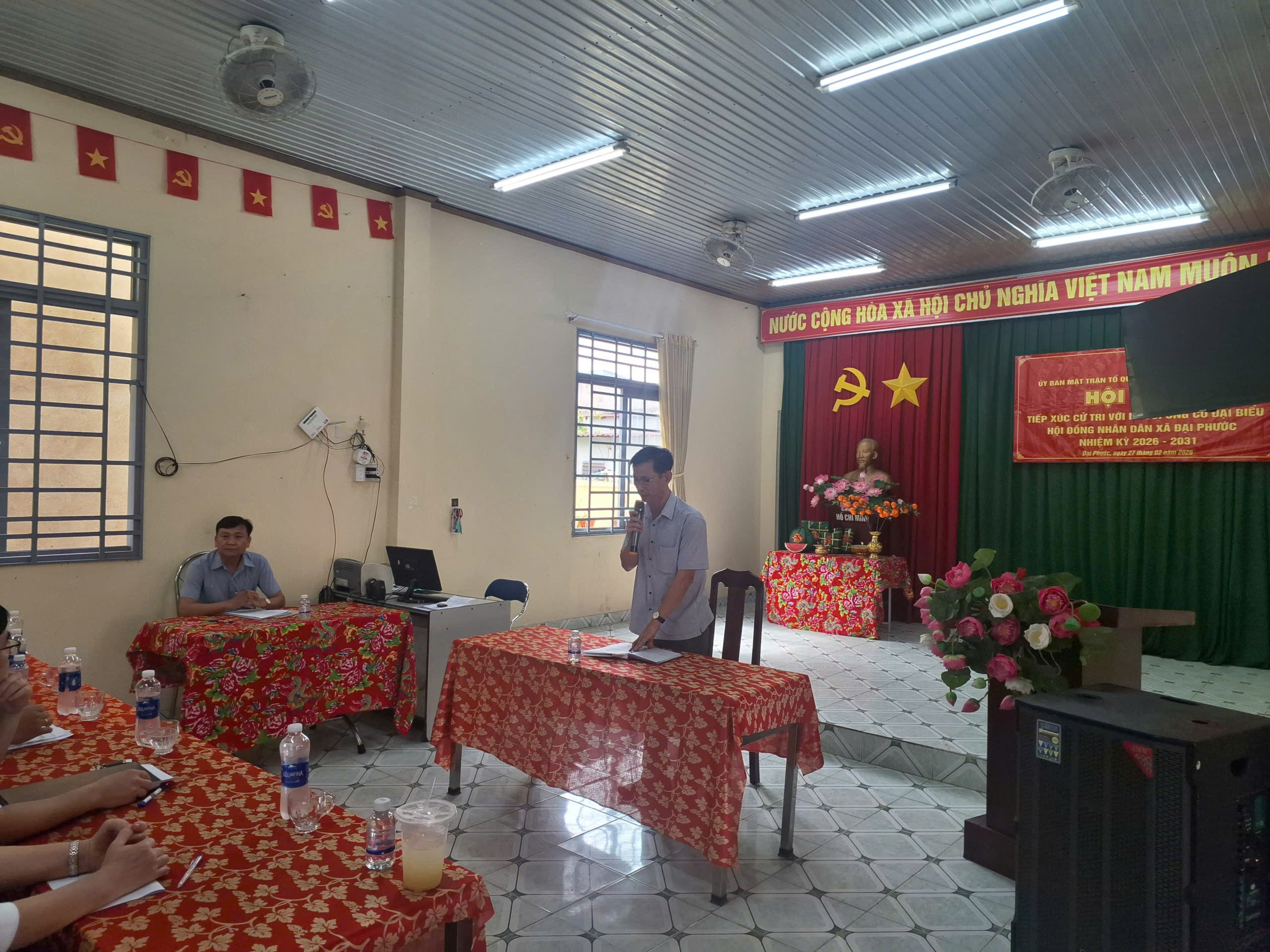 'A group of people sitting at tables in a room with red and green flags
Description automatically generated'
