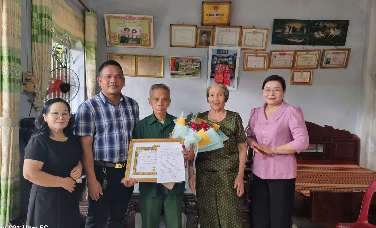 'The image shows a group of people standing in a room with decorations, a certificate, and various decorations on the wall.
AI-generated content may be incorrect.'