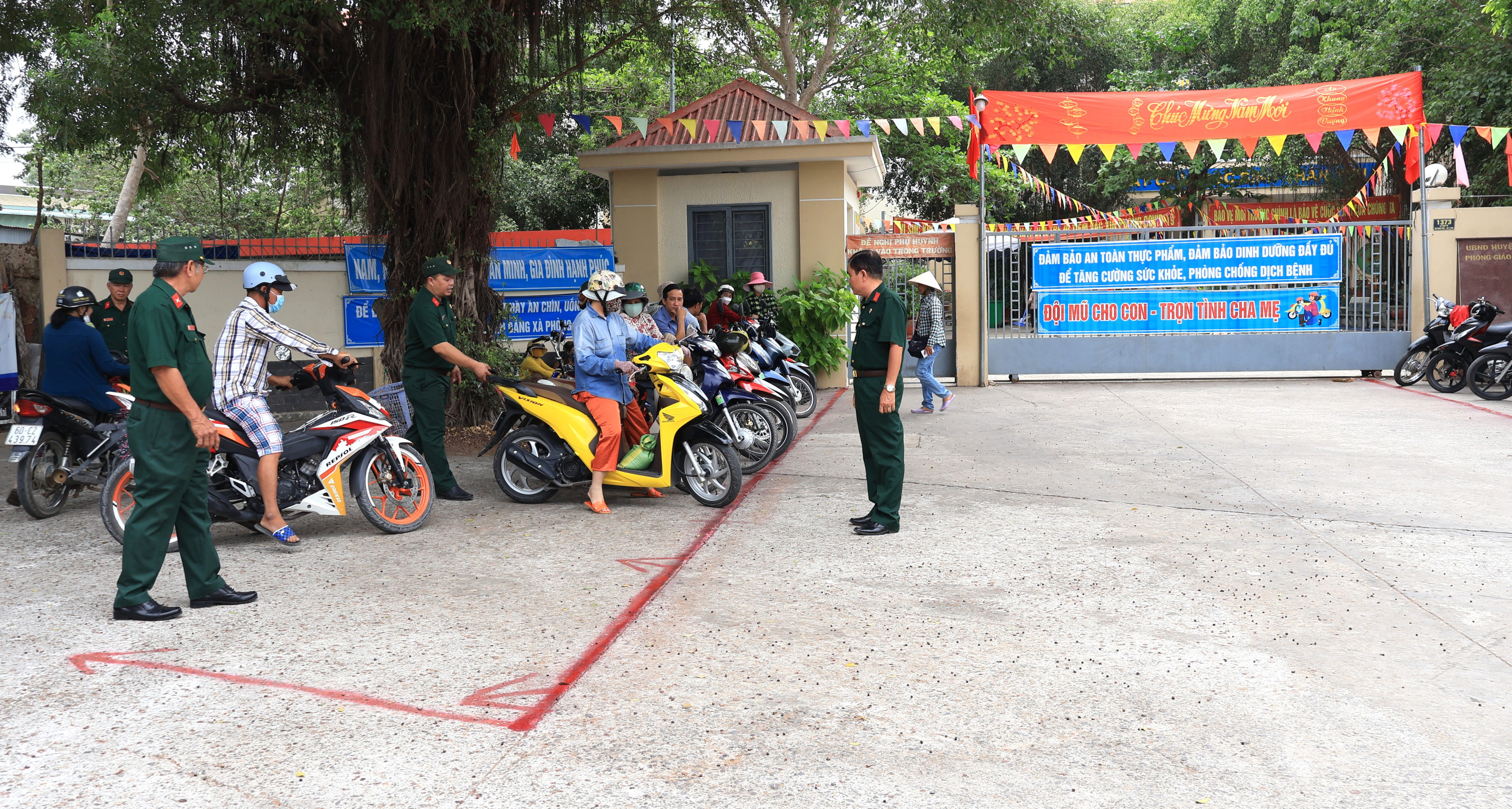 Cựu Chiến binh Tổ tự quản ANTT ấp Bình Phú nhiệt tình hướng dẫn phụ huynh đậu xe trước cổng trường, đảm bảo an toàn giao thông