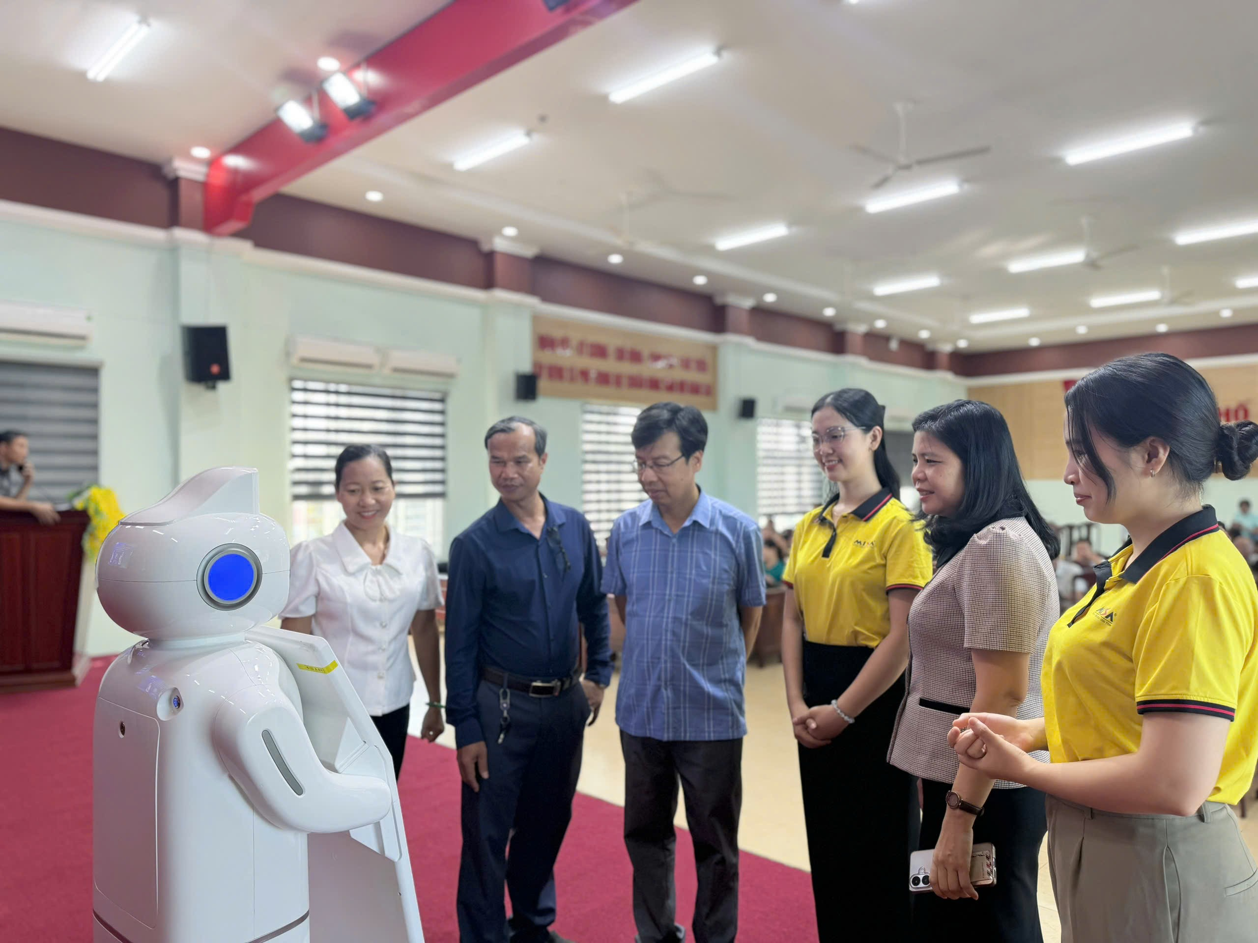 '''A group of people standing around a robot
Description automatically generated'''
