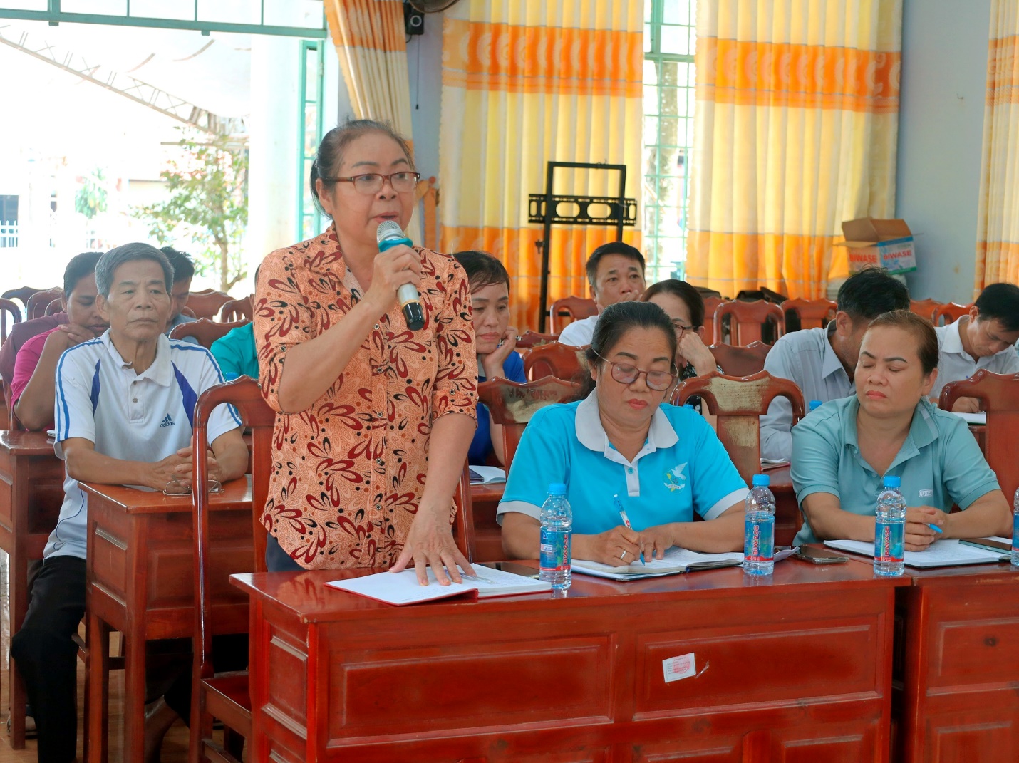 'A person speaking into a microphone in a classroom
Description automatically generated'