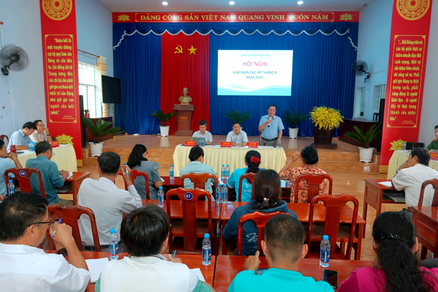 'A group of people sitting in chairs in front of a screen
Description automatically generated'