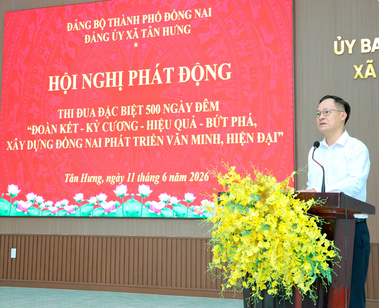 'A person standing at a podium with a large screen behind him
Description automatically generated'