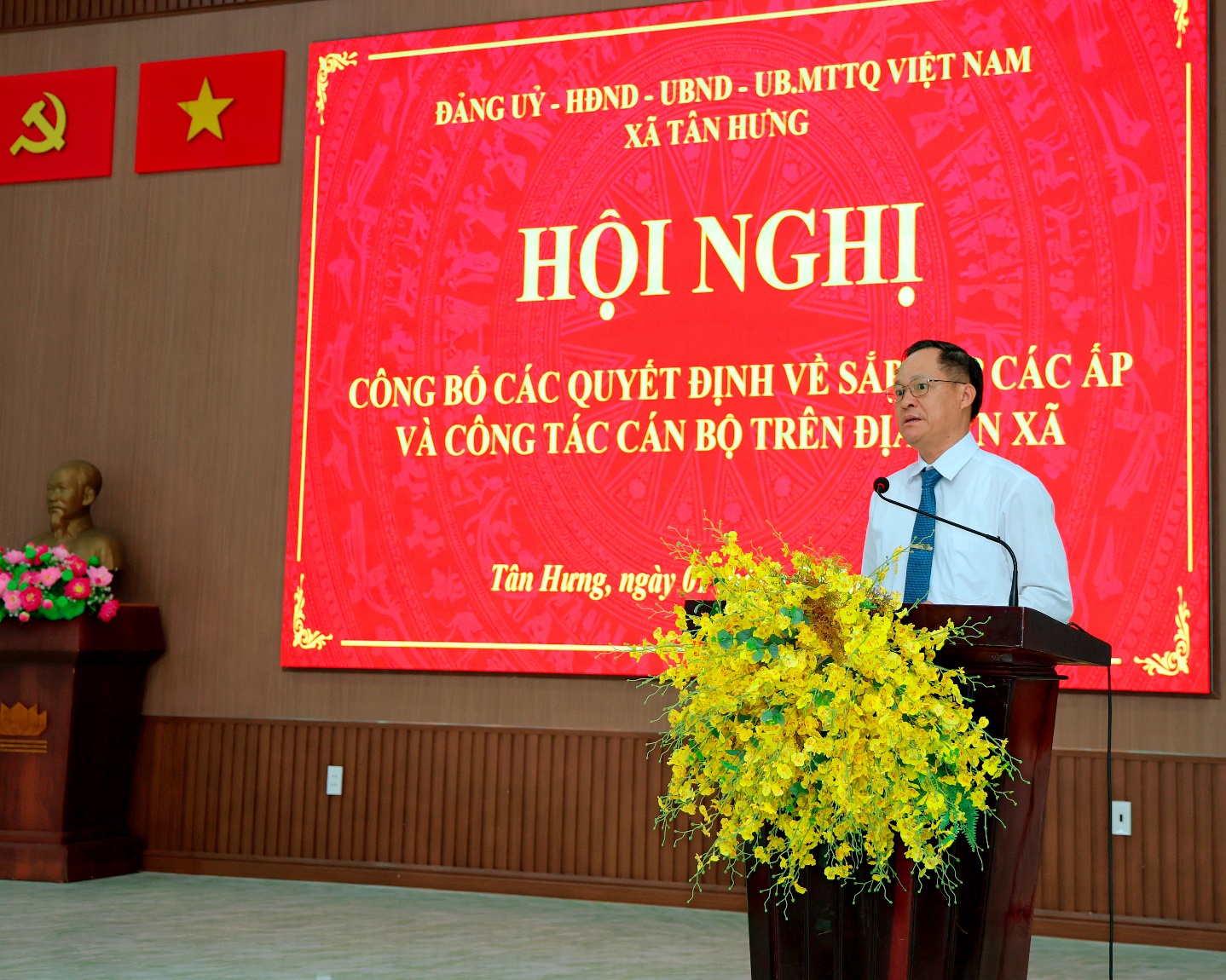 'A person standing at a podium with a large screen behind him
Description automatically generated'