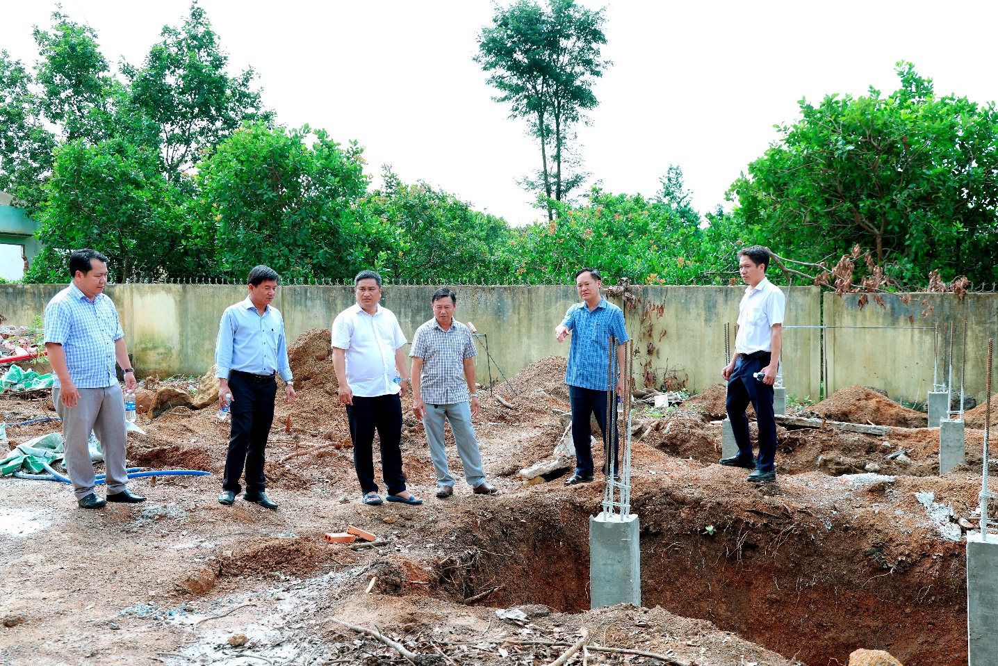 A group of men standing in a dirt area
Description automatically generated