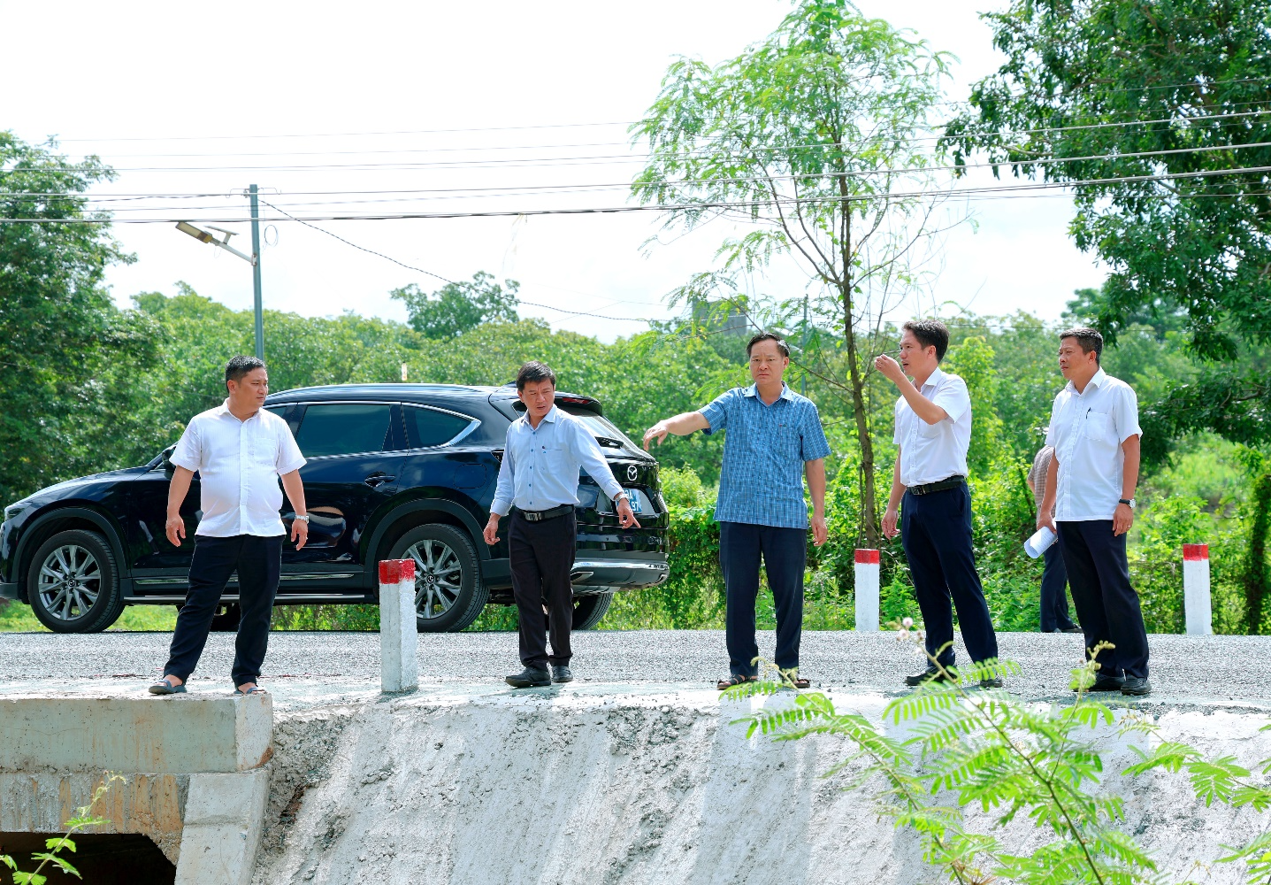 A group of men standing on a concrete ledge
Description automatically generated
