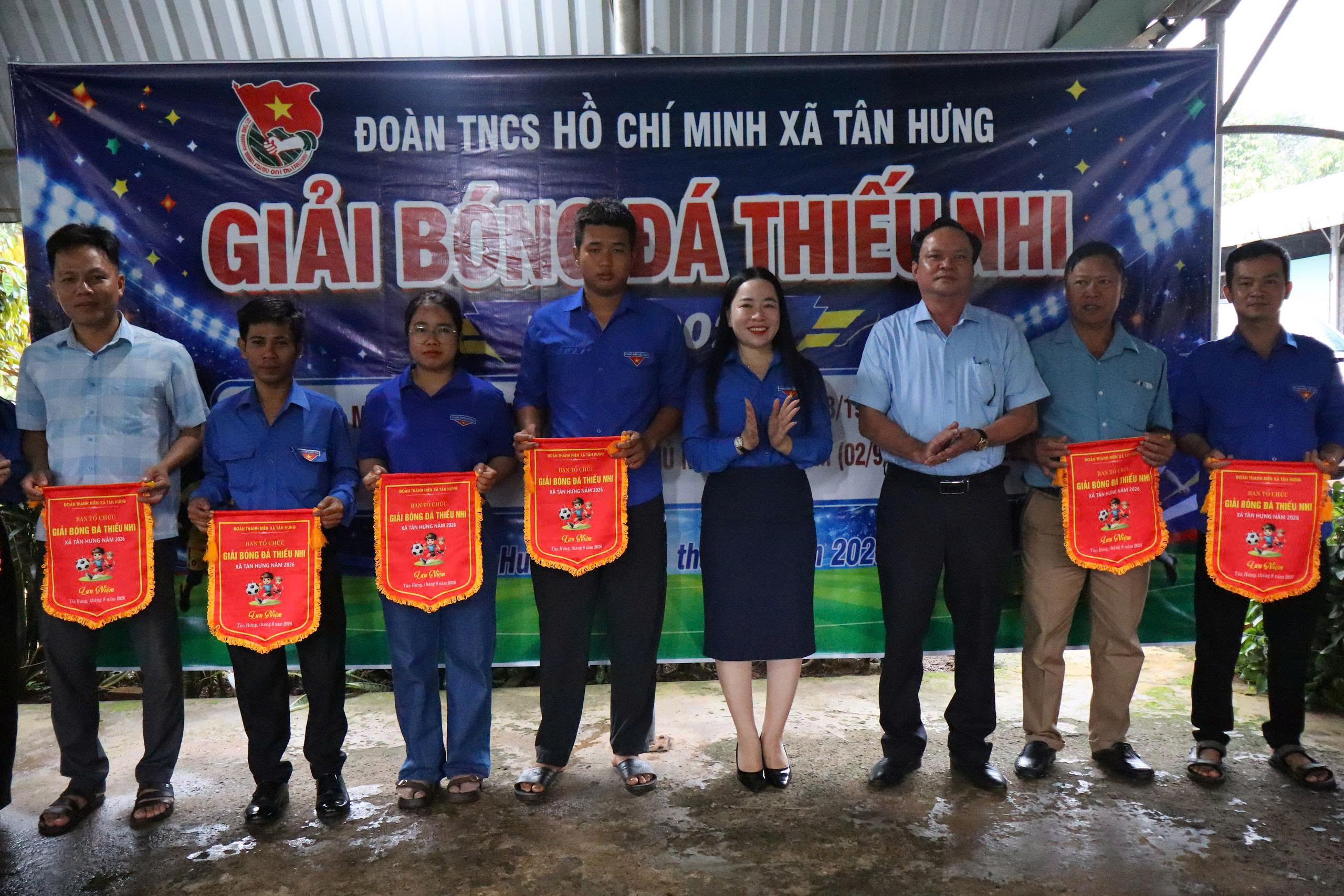 A group of people standing in front of a banner
Description automatically generated