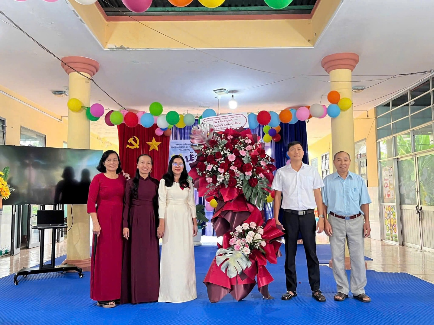 A group of people standing in front of a large flower arrangement
Description automatically generated