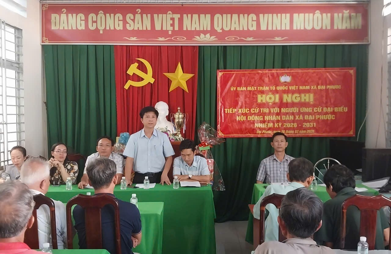 'A group of people sitting at tables in front of a red and green curtain

Description automatically generated'