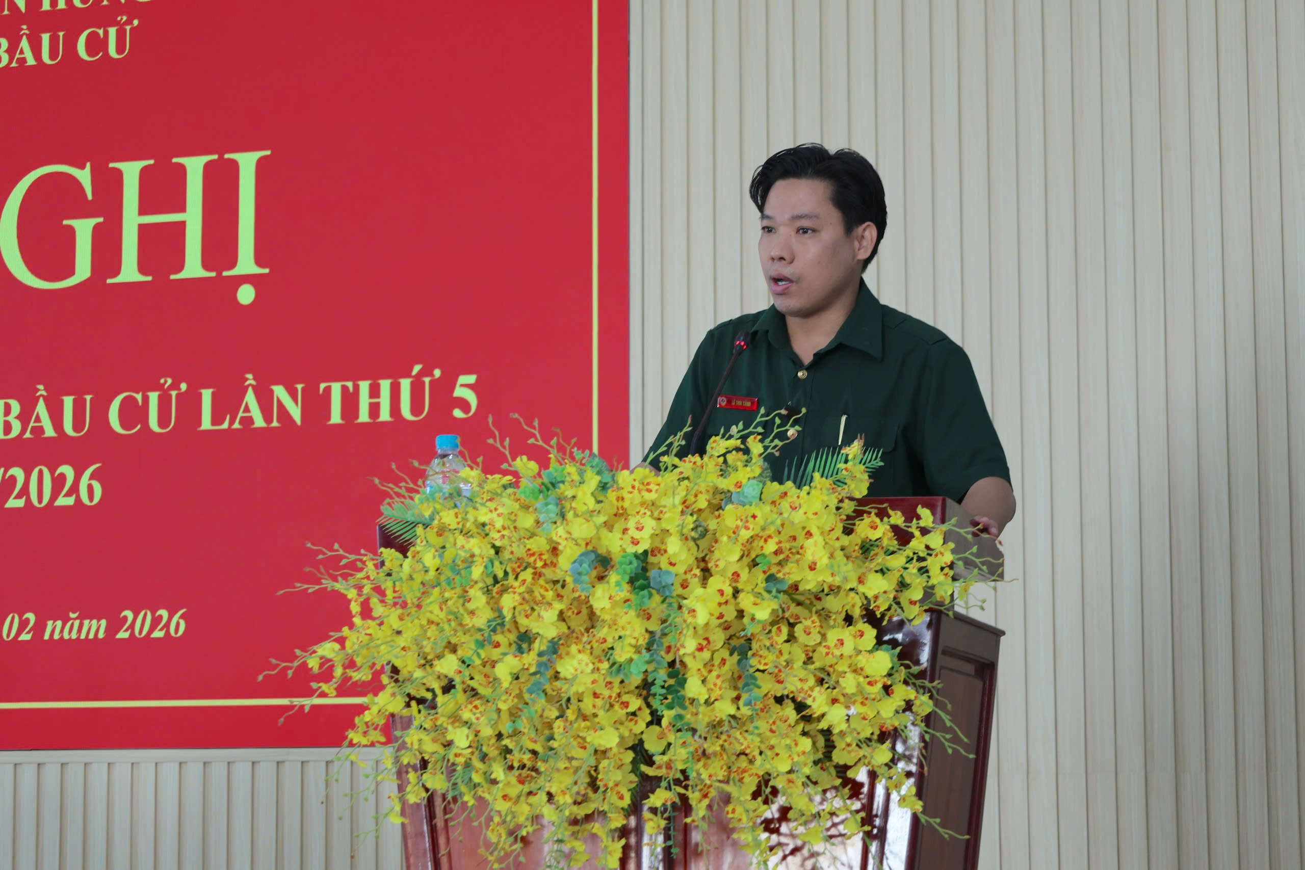 'A person standing at a podium with yellow flowers

Description automatically generated'