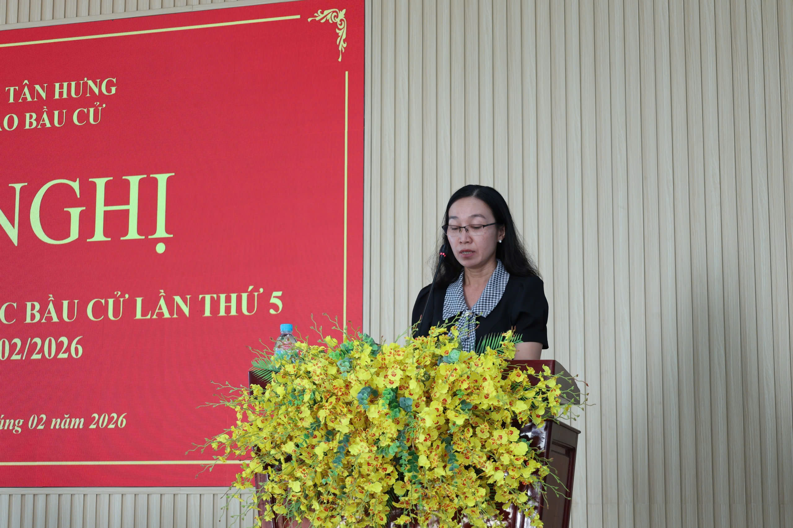 'A person standing at a podium with yellow flowers

Description automatically generated'