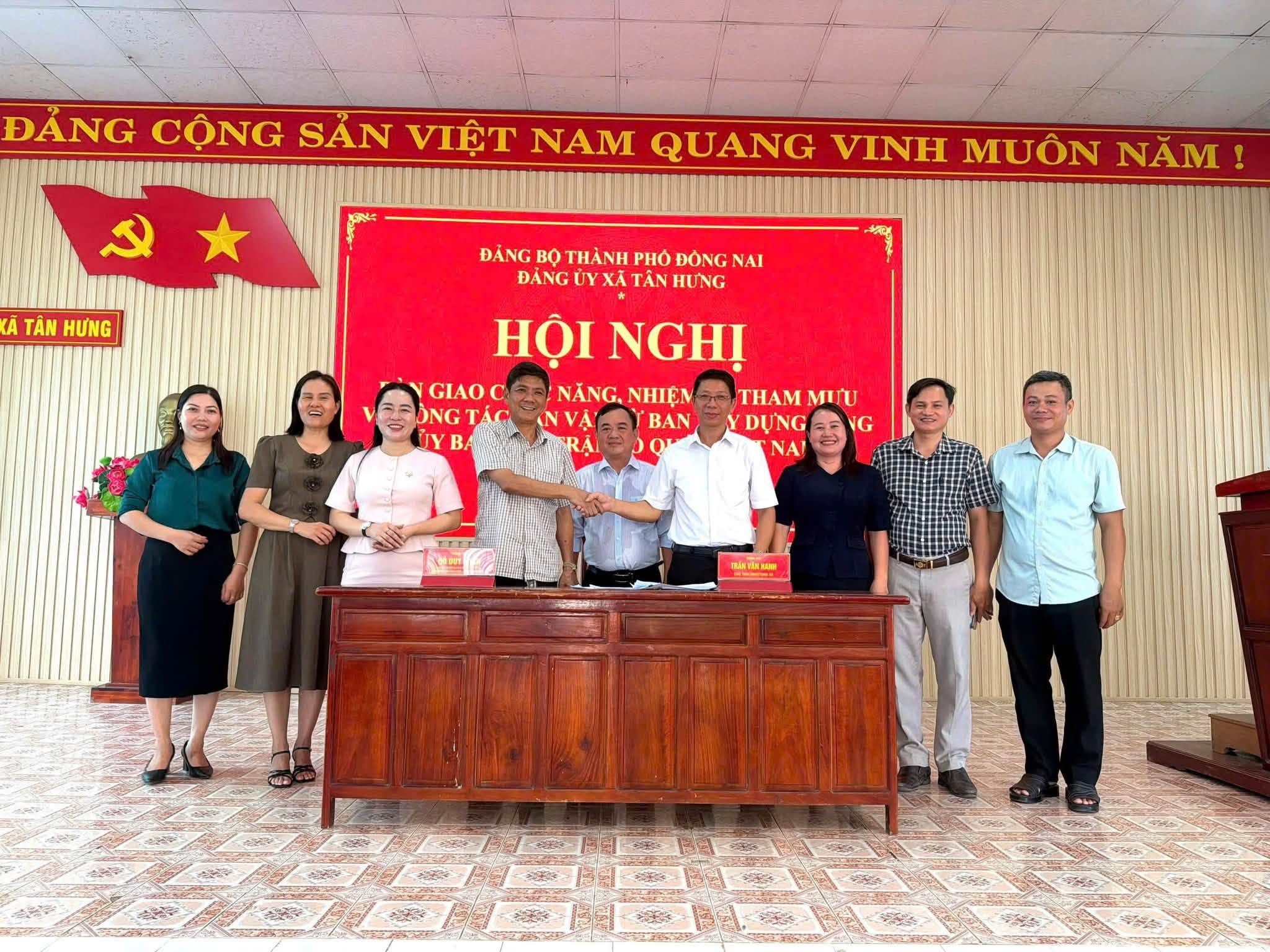 A group of people standing in front of a red banner

Description automatically generated
